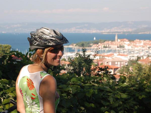 Radfahrerin vor Panoramablick auf Piran