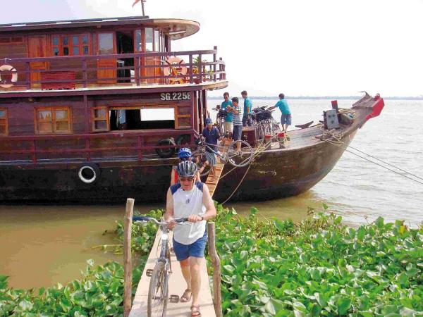 Radfahrer gehen waehrend der Radreise durch Vietnam von Bord einer Dschunke