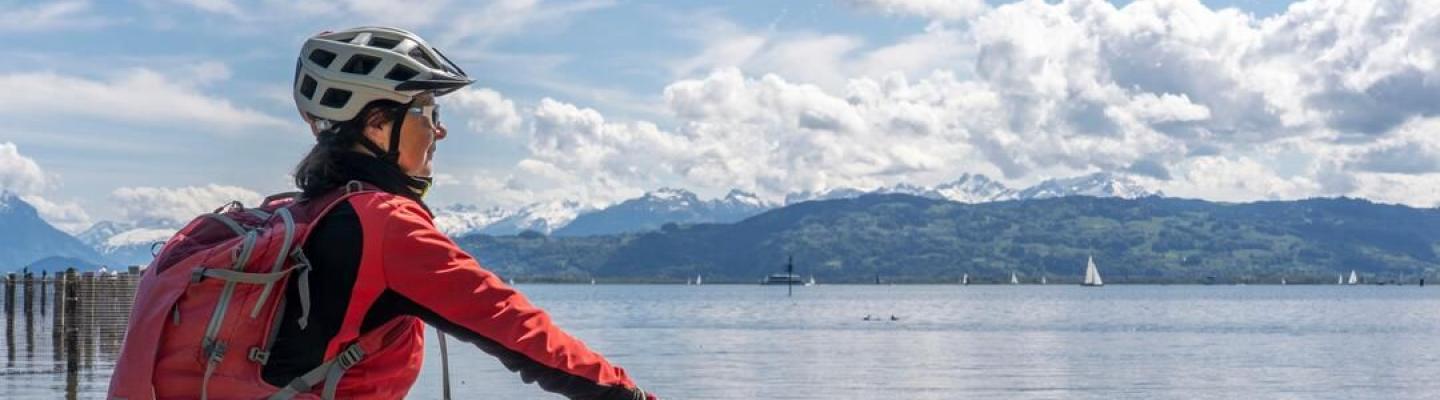 Radfahrerin am Bodenseeufer blickt auf den See | © 2021 Umomos/Shutterstock