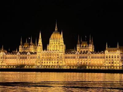 Ungarisches Parlament beleuchtet bei Nacht mit schimmernder Donau