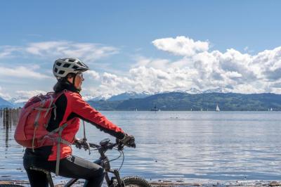 Radfahrerin am Bodenseeufer blickt auf den See
