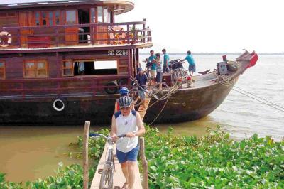 Radfahrer gehen waehrend der Radreise durch Vietnam von Bord einer Dschunke