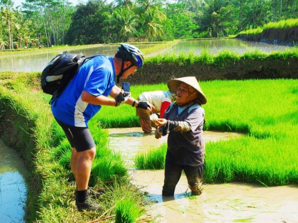 Radfahrer im Gesprch mit Reisbauer auf Bali