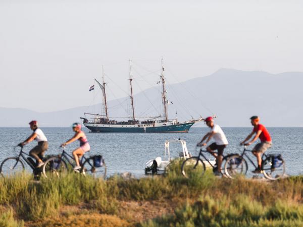 Radfahrer an der Kste der Toskana mit Schiff Atlantis
